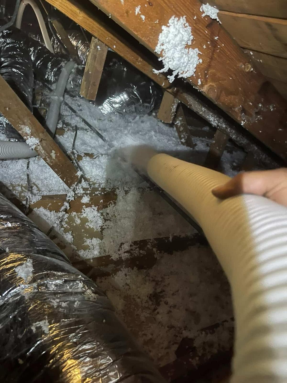 Insulation being blown into an attic crawlspace
